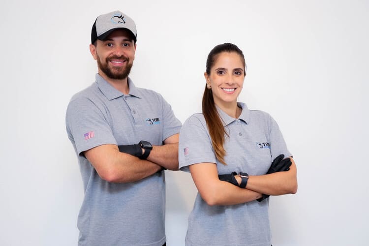 Casal braços cruzados com uniforme da empresa de limpeza